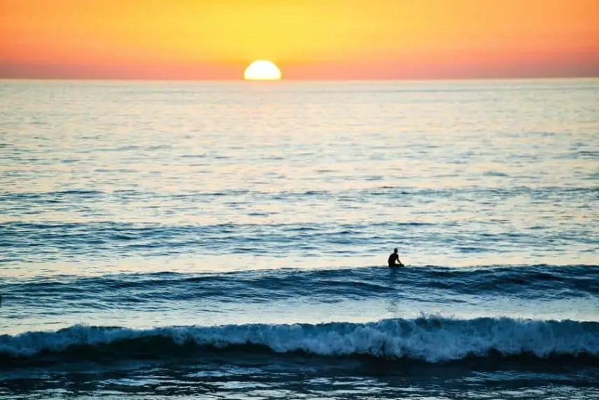 surfer in small waves at sunset
