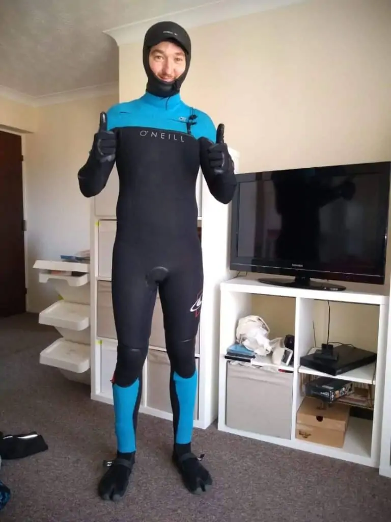 surfer standing in lounge with winter wetsuit, boots and gloves