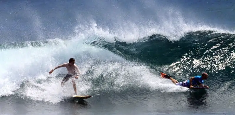 bodyboarder riding a wave in front of a surfer and dropping in