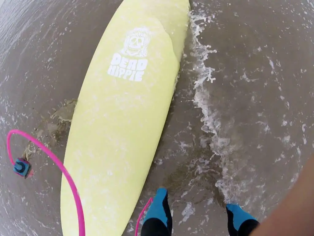 me standing over a foam surfboard with leash and wetsuit