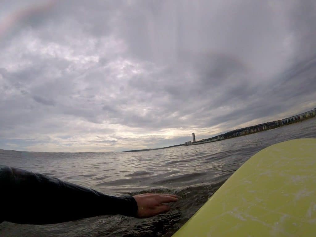 surfer looking out onto a grey sky after rain