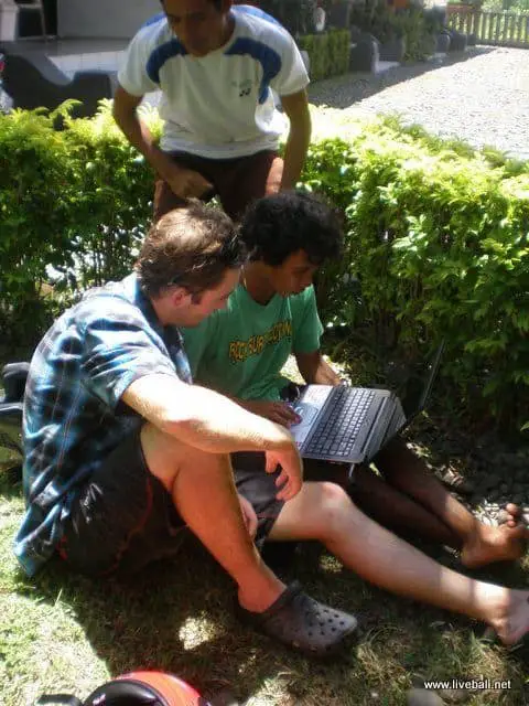 two men looking at surf photos on a laptop