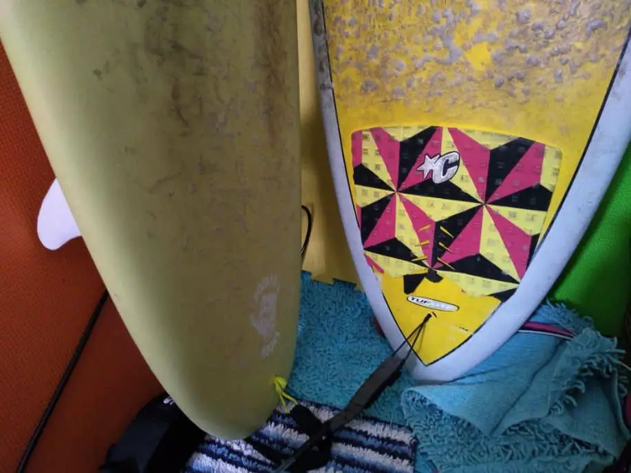 tail of two surfboards next to each other, one without a traction pad and one with a traction pad