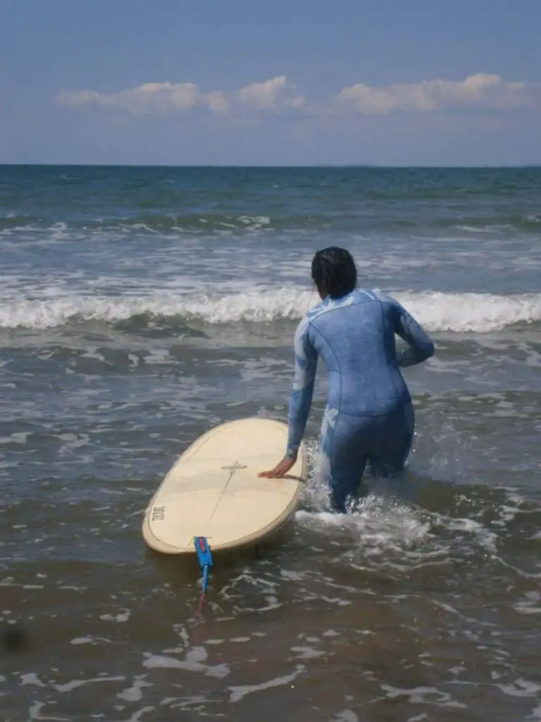 lady surfer walking out with a surfboard