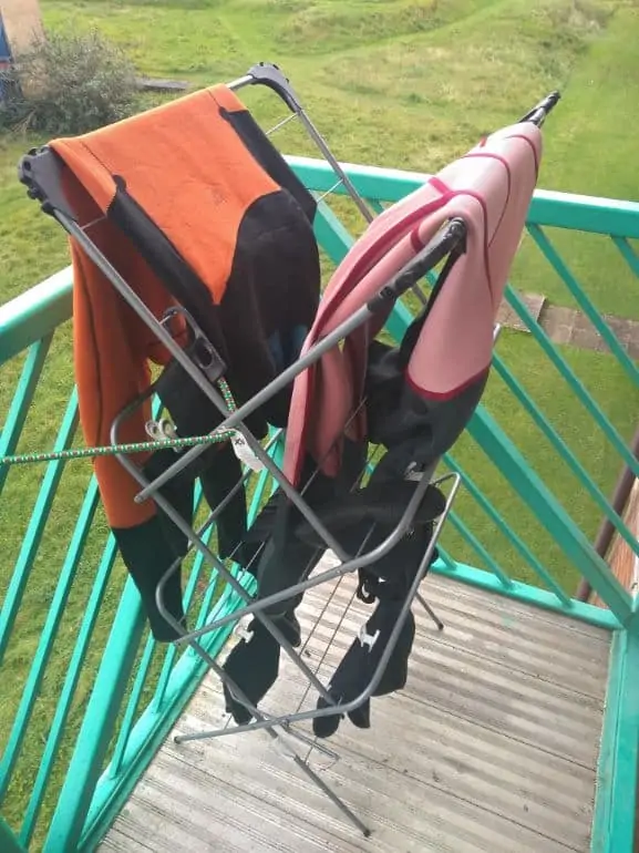 2 wetsuits hung out to dry on a laundry rack