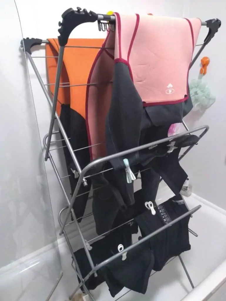 2 wetsuits on a laundry drying rack in the bath