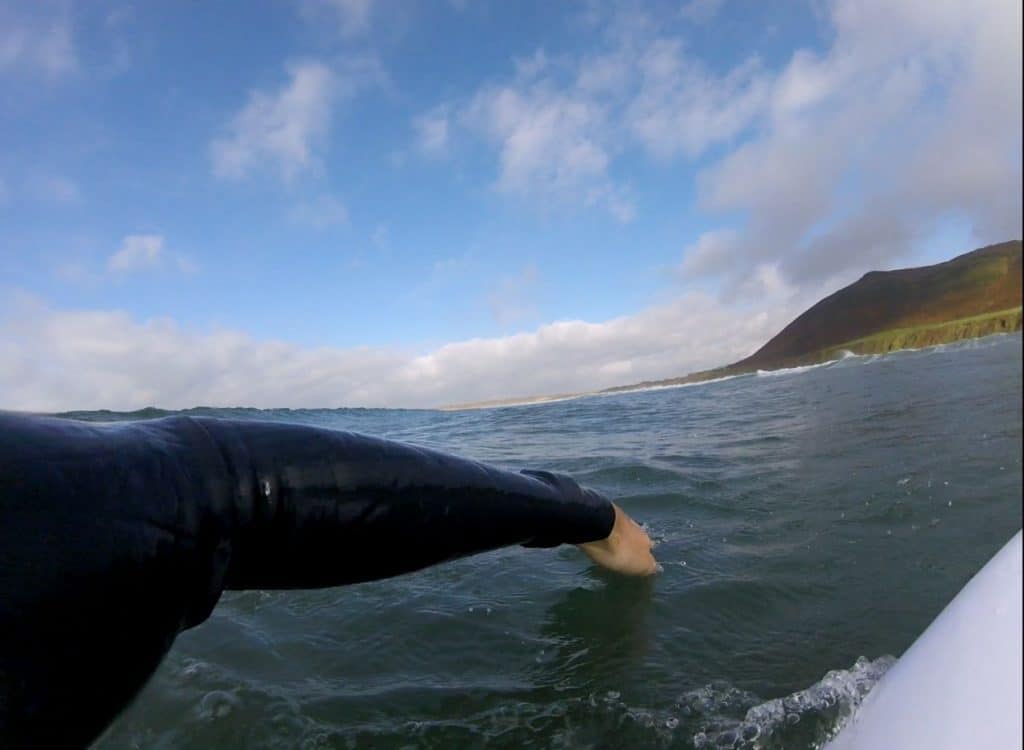 surfer's arm while paddling on a surfboard